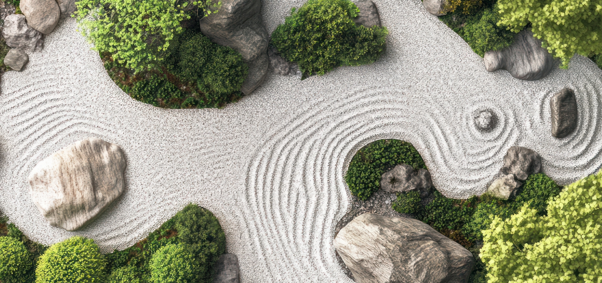 Aerial view of a Japanese Zen garden with raked white gravel, rocks, and green bushes. Curved lines and patterns form an infinite circle Zen motif around the stones, creating a tranquil, organized landscape.